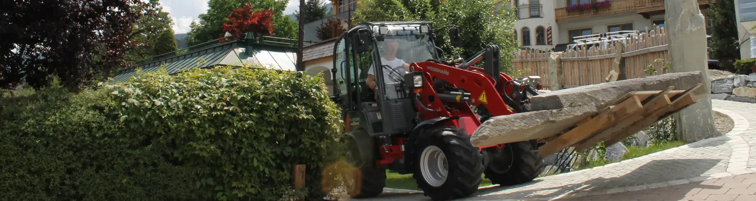 Ein Weidemann-Lader transportiert große Holzbalken vor dem Hotel Herrschaftstaverne.