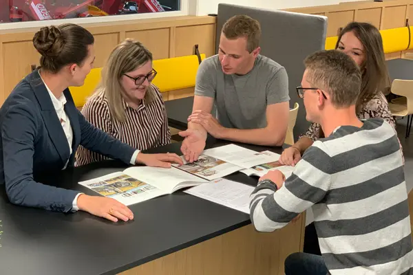 Personengruppe bei einer Besprechung mit offenen Geschäftsmaterialien auf einem Tisch im Büro.