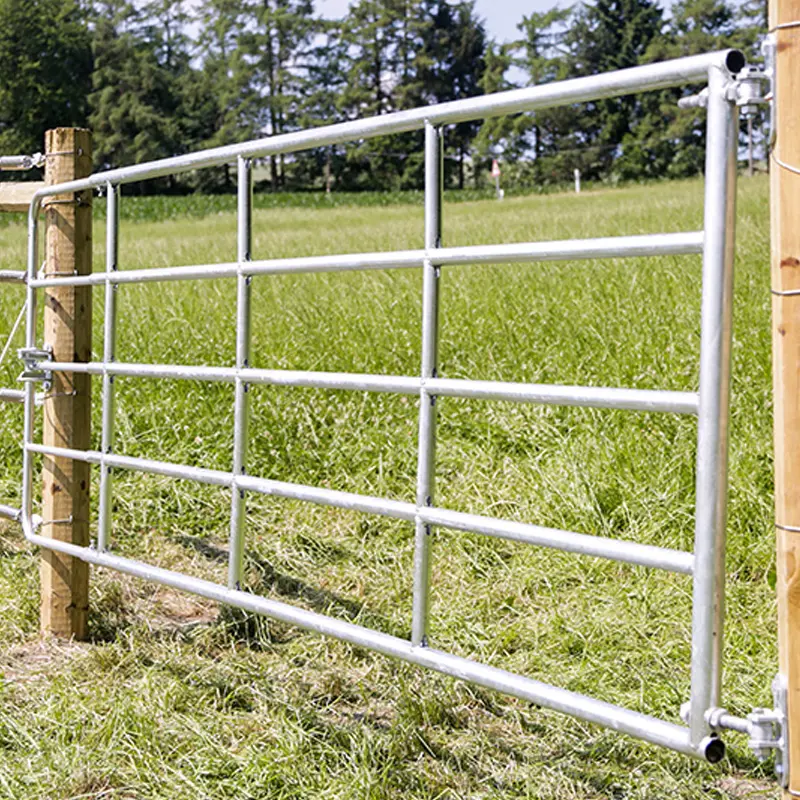 Metalltor für Weidetechnik, angebracht an Holzbalken in grünem Feld.