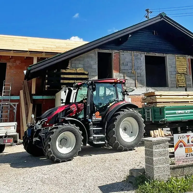 Ein Valtra G105 Active Traktor steht vor einem im Bau befindlichen Haus.