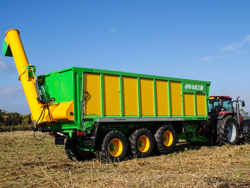 Joskin Transport Banda: vagon de transfer cu trei axe verde și galben cu conductă de descărcare în spatele tractorului pe câmp