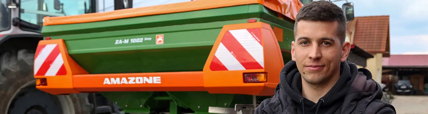 Bărbat în curte, în fața unui distribuitor de îngrășăminte AMAZONE ZA-M 1002 verde și portocaliu, în incinta companiei Mauch.