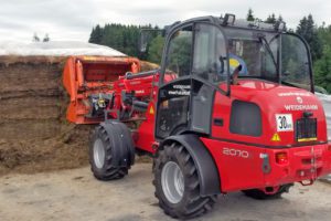Weidemann 2070 LP DX Traktor, der Heuballen stapelt.