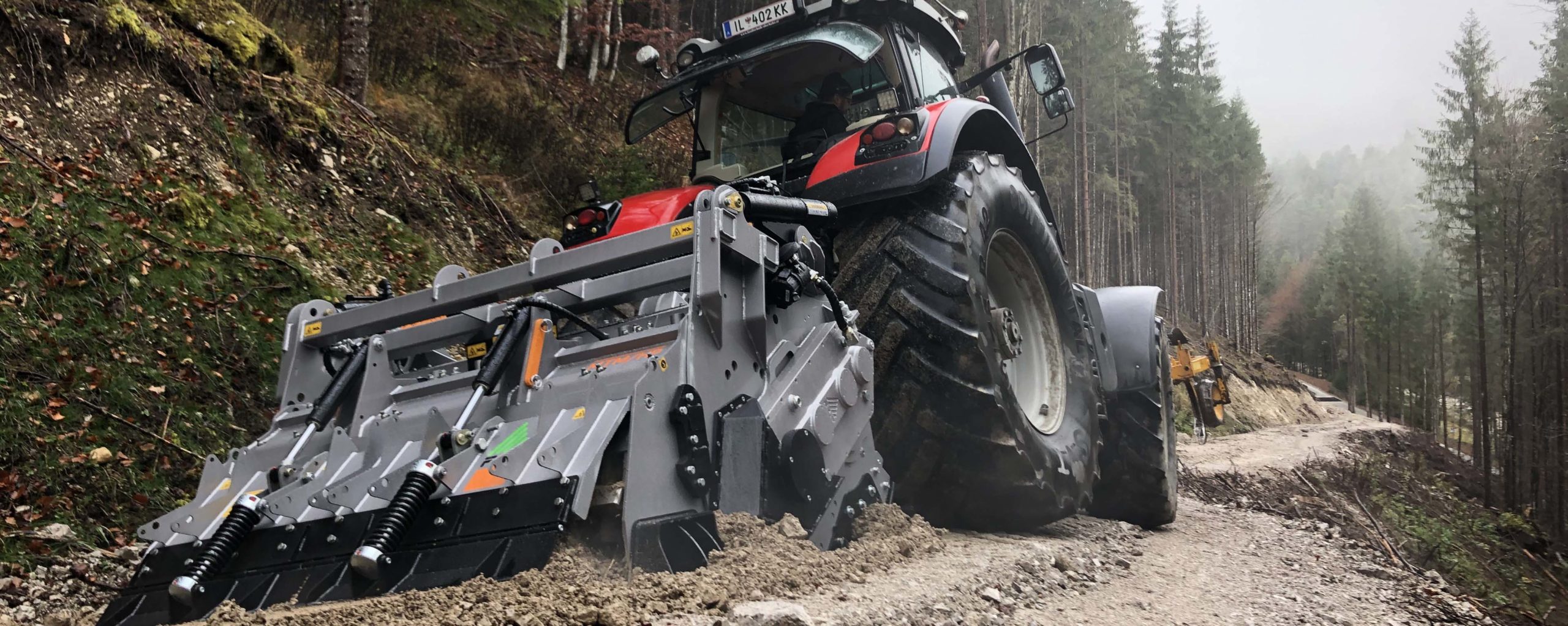 Traktor fährt auf einem Waldweg und benutzt einen FAE MTMHP200 Mulcher.