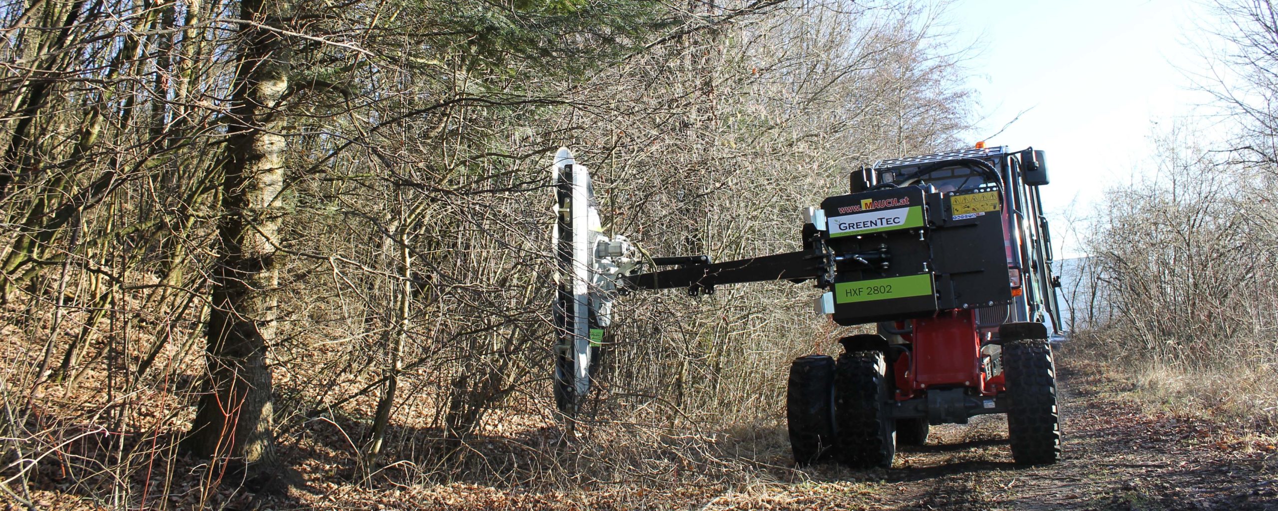 Ein Greentec HXF 2802 Maschinenfahrzeug schneidet Äste in einem Wald.