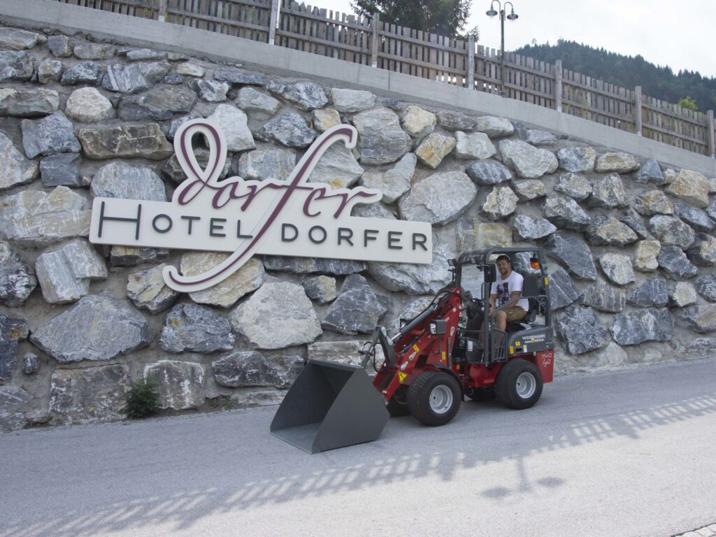 Uomo su un escavatore davanti all&#039;Hotel Dorfer-Schild.