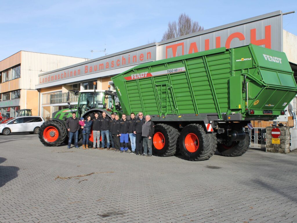 Група позира испред зеленог Fendt Tigo 60 PR D испред зграде са натписом Landmaschinen Baumaschinen Mauch.