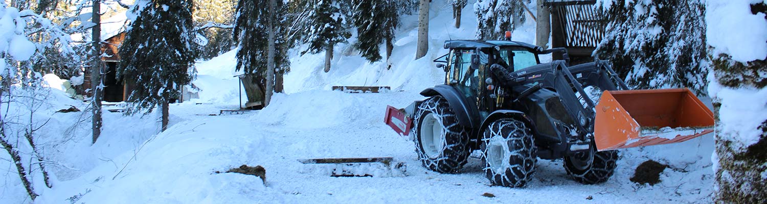Ein VALTRA-A74 Traktor fährt auf einem verschneiten Waldweg.
