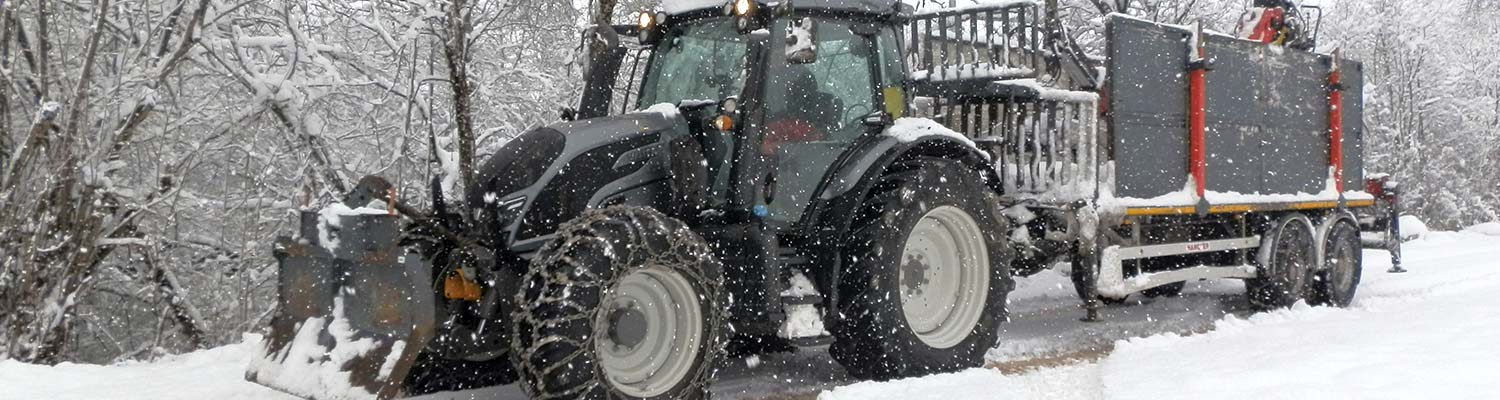 Traktor Valtra N174 DIR zieht Anhänger durch verschneite Landschaft.