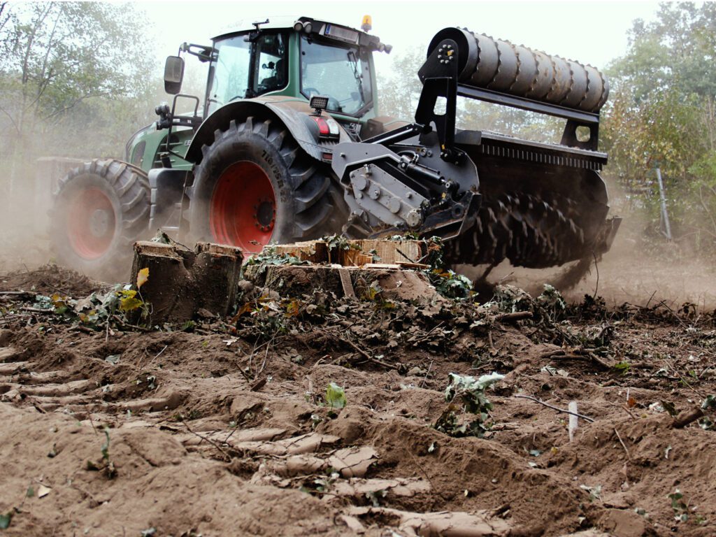 Трактор меље пањ на пољу.