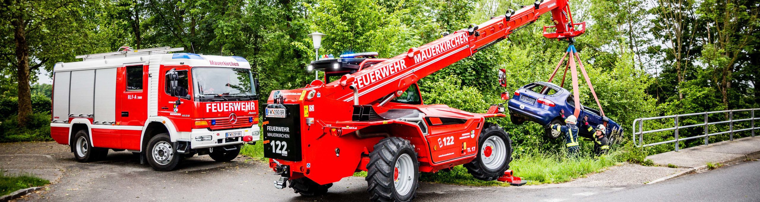 Feuerwehrfahrzeuge in Mauerkirchen bergen ein Auto mit einem Merlo Kran.