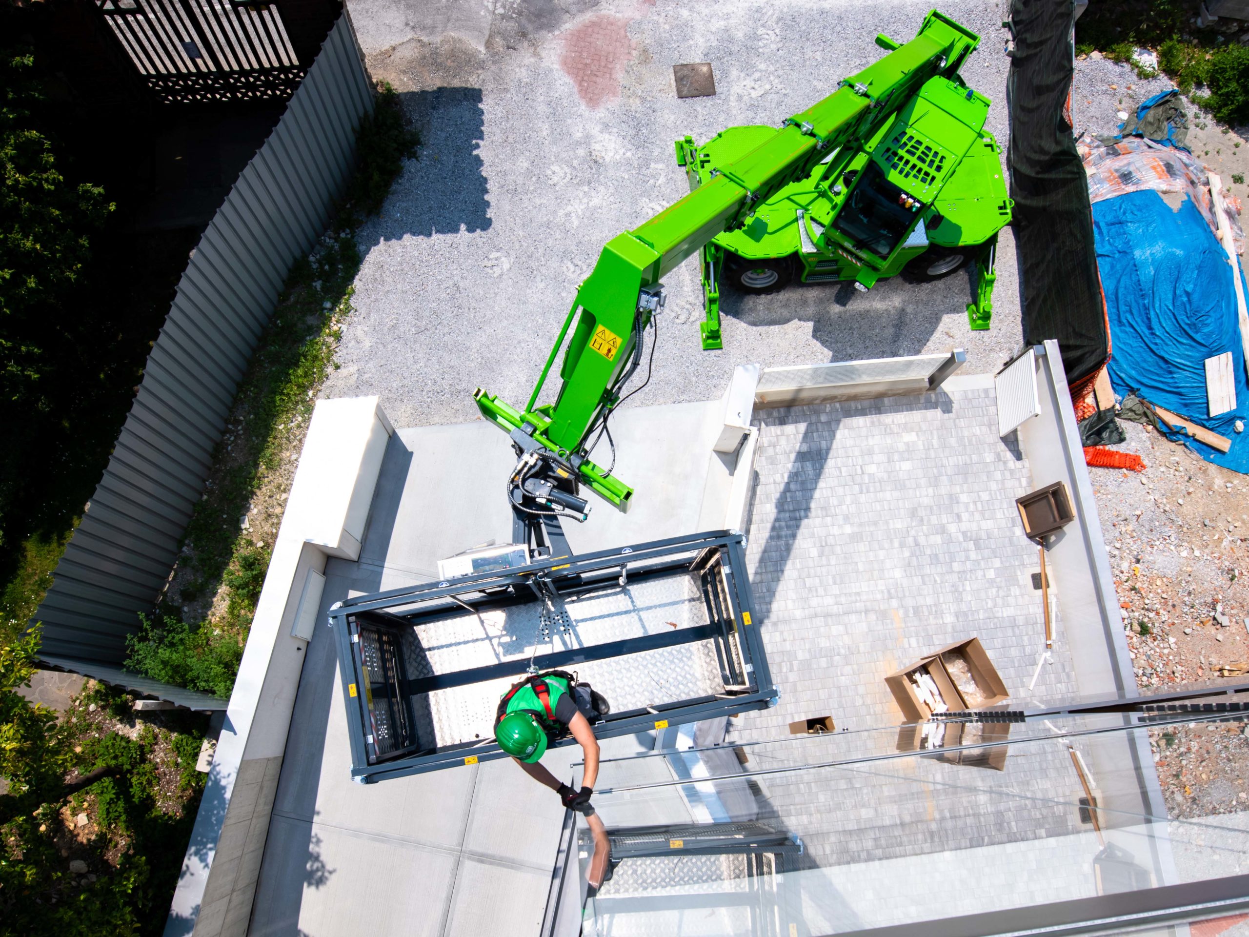 Ein grüner Merlo ROTO 40.18 Teleskoplader hebt eine Arbeitsplattform mit einem Bauarbeiter.