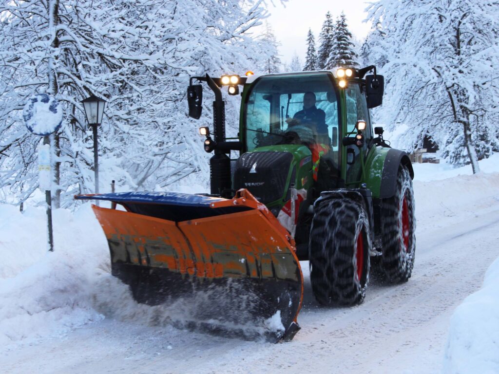 Traktor Fendt 312 s ralicom za snijeg čisti cestu prekrivenu snijegom.