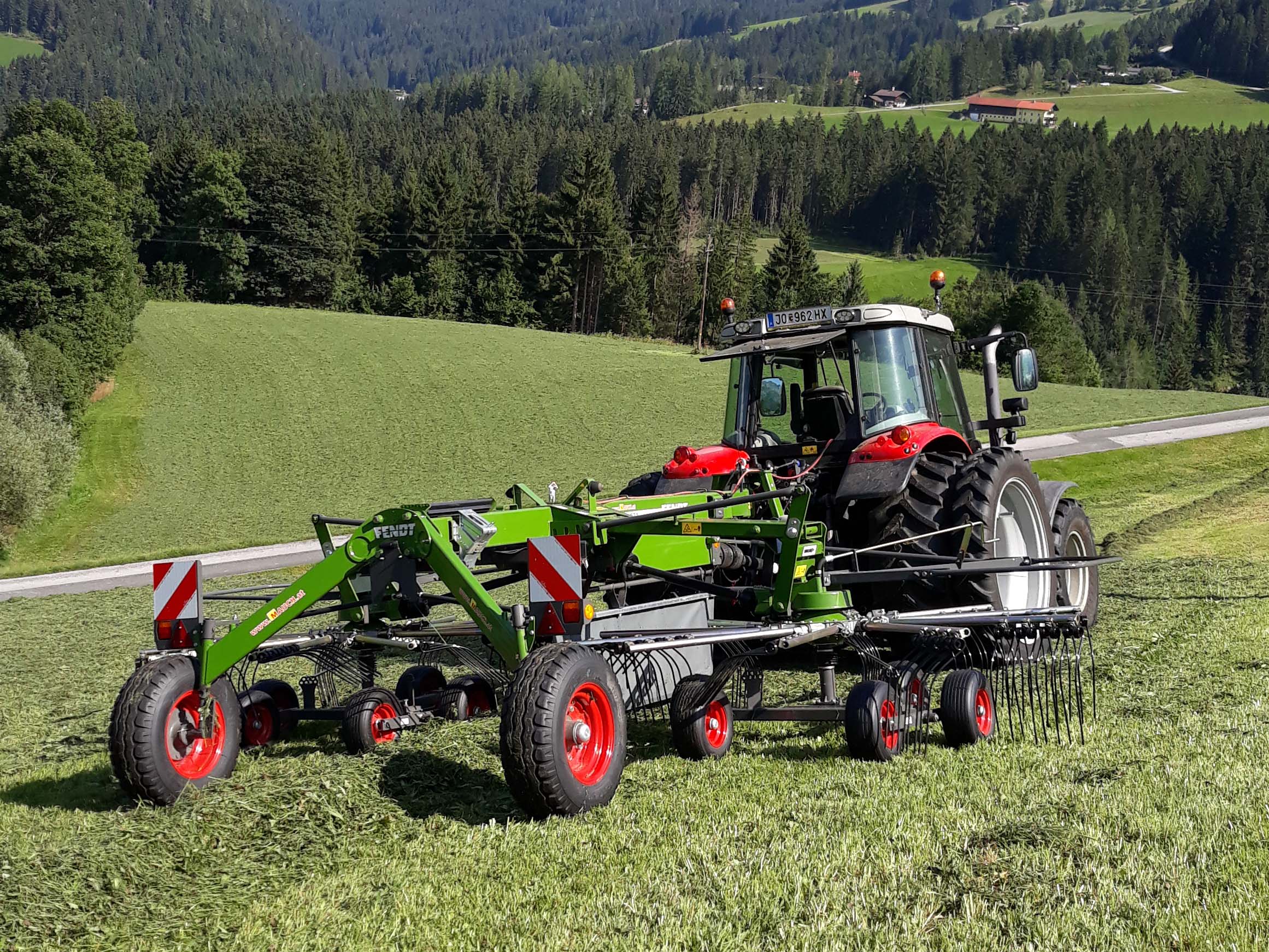 Traktor zieht einen Fendt Former Heuwender auf einem Feld.