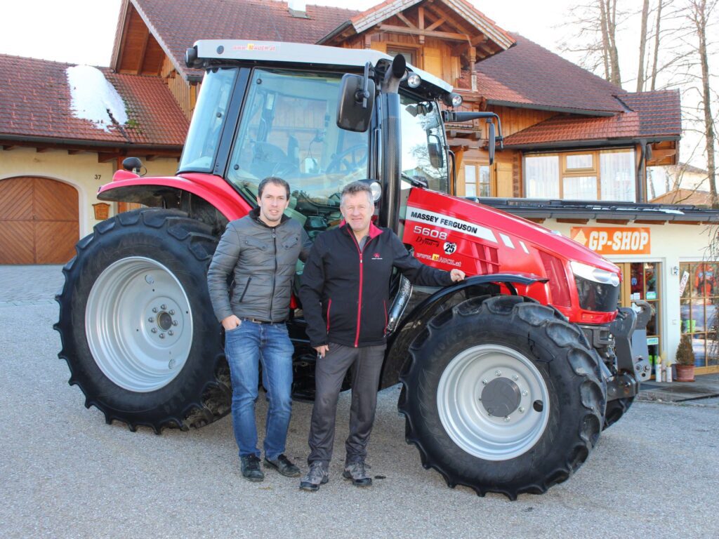 Zwei Männer stehen vor einem Massey Ferguson 5608 Traktor vor einem Gebäude mit einem GP-Shop.