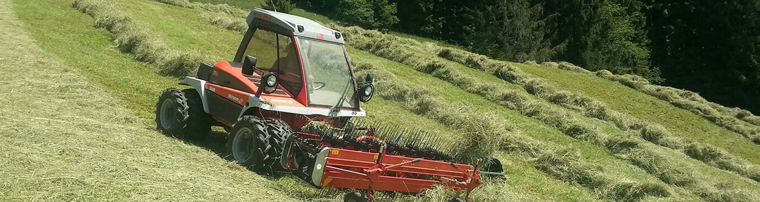 Ein Reform-Mahgerät bearbeitet ein Feld mit frisch geschnittenem Gras.