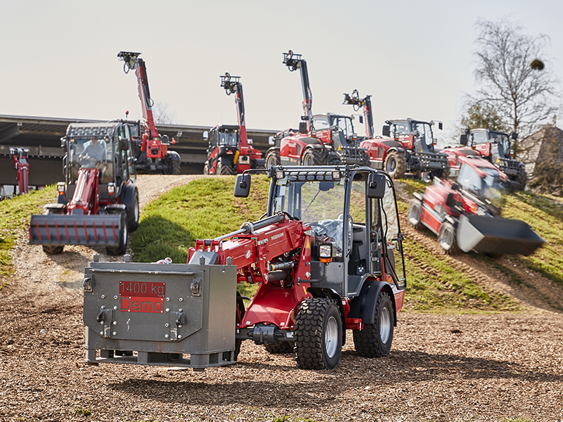 Mehrere rote Bagger auf einem Hügel im Demogelände, ein Bagger trägt ein 1400 kg Gewicht.