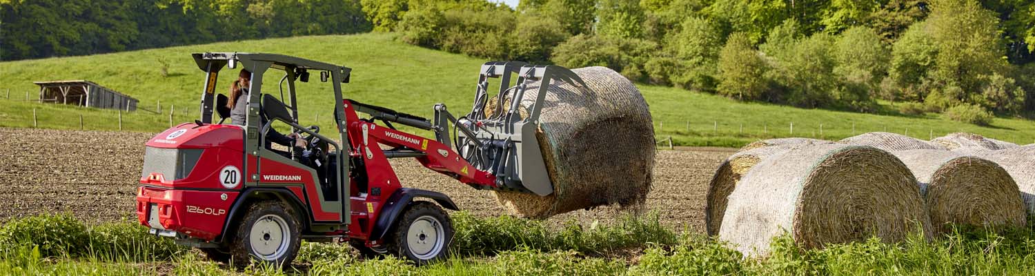 Weidemann 1260LP Radlader transportiert eine Heuballe auf einem Feld.