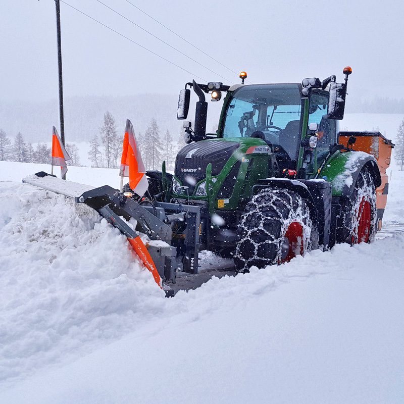 Traktor Fendt 718 räumt eine schneebedeckte Straße.