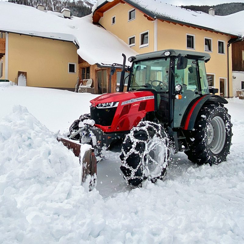 Ein roter Massey Ferguson 3707 AL Traktor räumt Schnee vor einem gelben Haus.